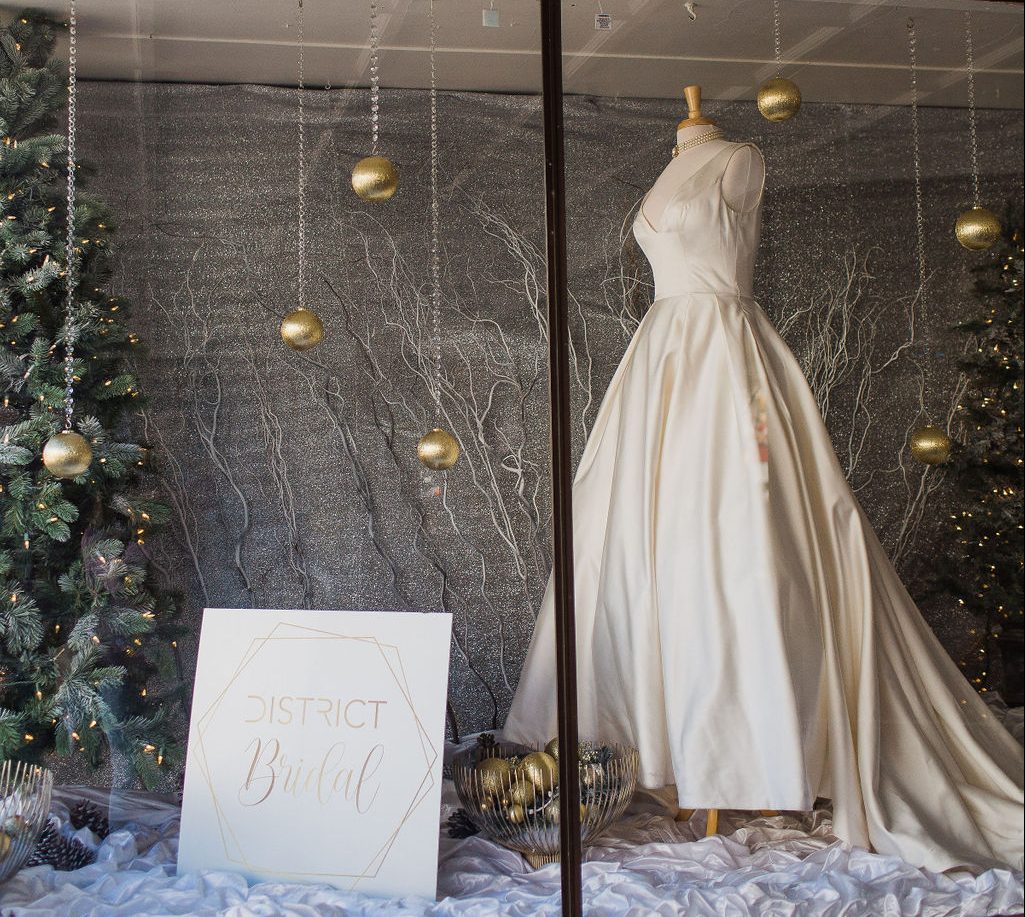 District Bridal in Downtown DeLand storefront window with a satin wedding gown.